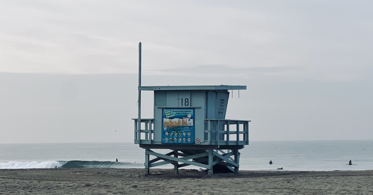 Lifeguard tower 18 on an overcast Venice Beach with surfers in the water
